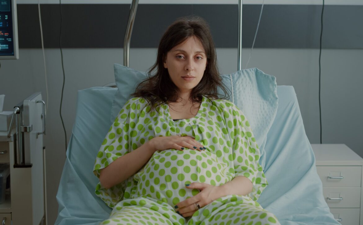 Portrait of pregnant woman laying in hospital ward bed